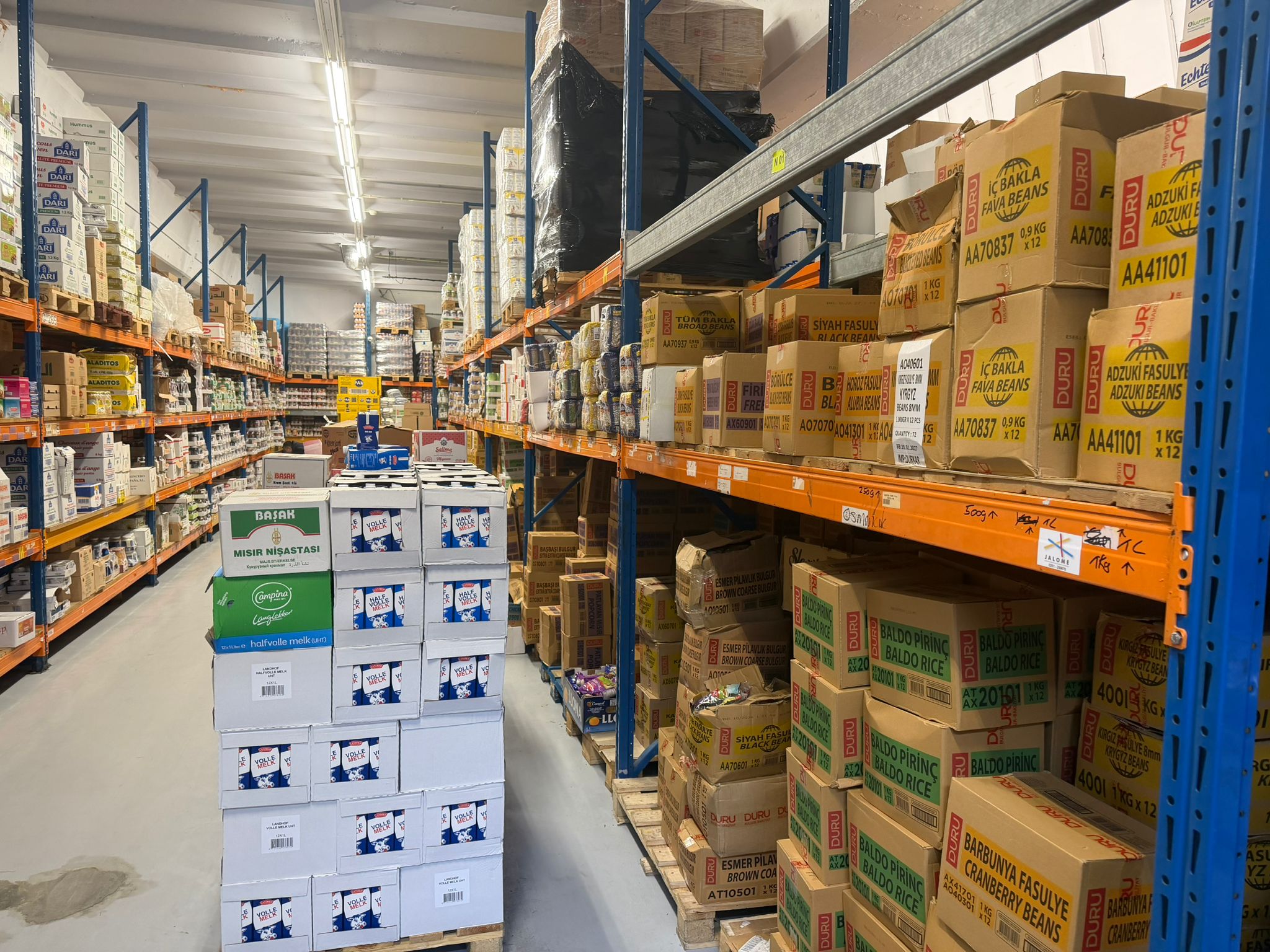 Gangpad met levensmiddelen en voorraad bij IG Impex aan de Vredenhofweg